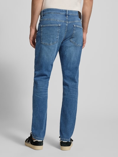 Männermodel trägt Slim Fit Jeans aus Baumwoll-Mix Modell 'LOOM' von Only & Sons in mittelblauem Denim mit Label Patch, Ganzkörperansicht Rückansicht.