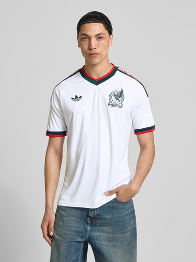 Männermodel trägt Auswärtstrikot Mexico 2026 von adidas Sportswear, Mehrfarbig, Slim-Fit, V-Ausschnitt, Kurzarm, Applikation, Ganzkörperansicht von vorne.