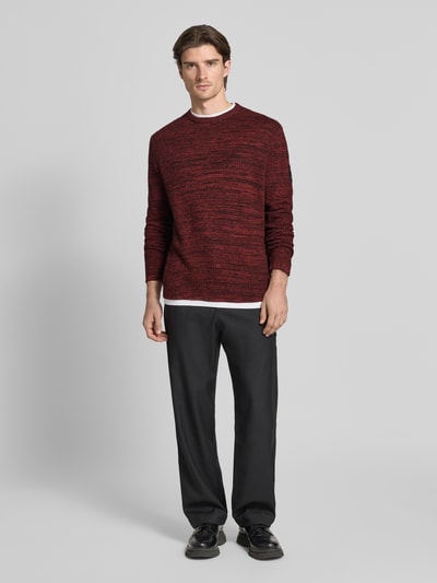 Männermodel trägt Regular Fit Strickpullover aus Baumwoll-Mix von Tom Tailor Denim in rot-melierter Optik mit Strukturmuster, Ganzkörperansicht von vorne.