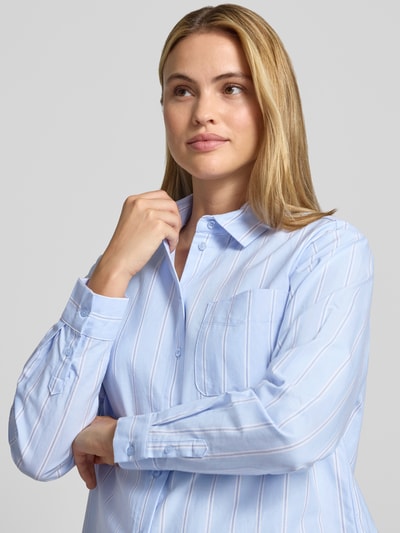 Frauenmodel trägt Regular Fit Hemdbluse aus reiner Baumwolle von Christian Berg Woman, hellblaue und weiße Streifen, Brusttasche, Nahaufnahme Oberkörper.