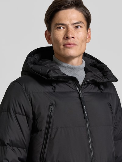Männermodel trägt Regular Fit Daunenjacke mit Kapuze von Marc O'Polo in Schwarz, wasserabweisend, Label Patch, Nahaufnahme Oberkörper.