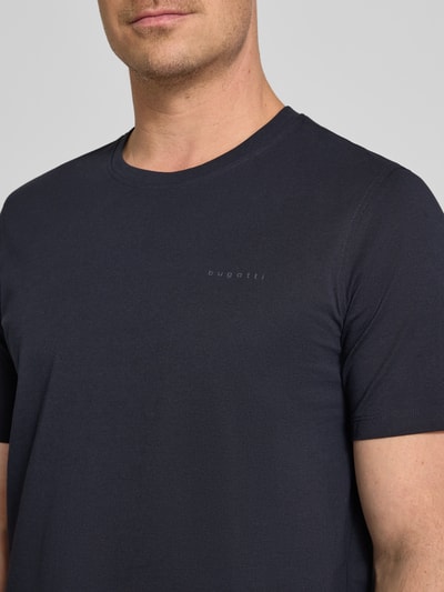 Männermodel trägt dunkelblaues T-Shirt mit Label-Detail von bugatti aus reiner Baumwolle, gerader Schnitt, Nahaufnahme Oberkörper.