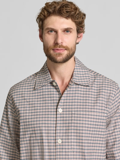 Männermodel trägt Freizeithemd mit Umlegekragen aus reiner Baumwolle von Selected, kariertes Allover-Muster, Nahaufnahme Oberkörper.