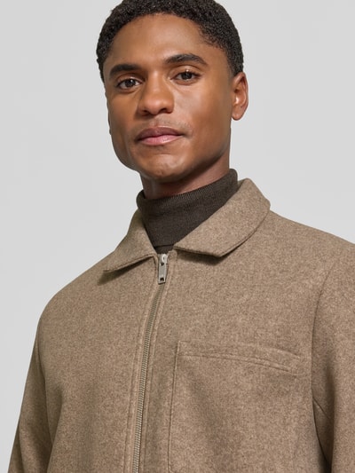 Männermodel trägt Jacke mit Brusttasche und Kentkragen Modell 'ROLFSTED' von Casual Friday in Beige, Nahaufnahme Oberkörper. Gerader Schnitt, Reißverschluss, strukturierte Textur, Kontext: Rückenlänge 62 cm, Schulterbreite 42 cm, Brustweite 51 cm, Ärmellänge 66 cm.