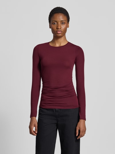 Kobiece modelka nosi bluzkę z długim rękawem Slim Fit Langarmshirt aus Lyocell-Mix model 'AVA' od VERO MODA, bordowy kolor, prosta faktura, przód, ujęcie całopostaciowe.