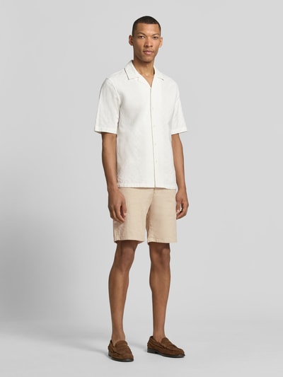 Männermodel trägt Regular Fit Chinoshorts aus Baumwoll-Leinen-Mix Modell 'BRODY' von SELECTED HOMME in Beige, Ganzkörperansicht von vorne. Unifarben mit Gürtelschlaufen, Knopf, verdecktem Reißverschluss und seitlichen Eingrifftaschen, feine Flammgarnstruktur.