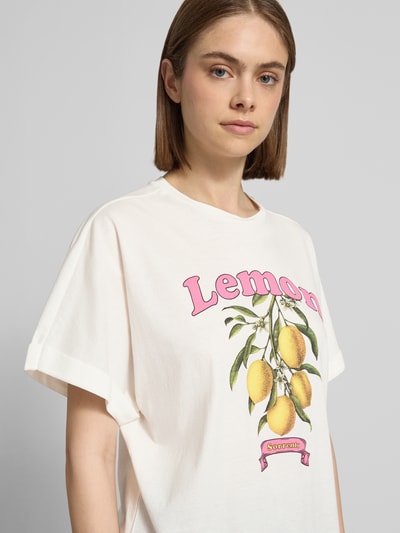 Frauenmodel trägt Boxy Fit T-Shirt aus reiner Baumwolle Modell 'MINNA' von Only, unifarben, Motiv-Print Zitrone, Nahaufnahme Oberkörper.