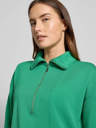 Vrouwenmodel draagt Sweatshirt met Umlegekragen van Christian Berg Woman in felgroen, zachte textuur, korte rits, Nahaufnahme bovenlichaam.