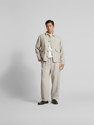 Männermodel trägt Hemdjacke aus reinem Leinen von Closed in Beige, Regular Fit, Pattentaschen, glatte Textur, Ganzkörperansicht von vorne.