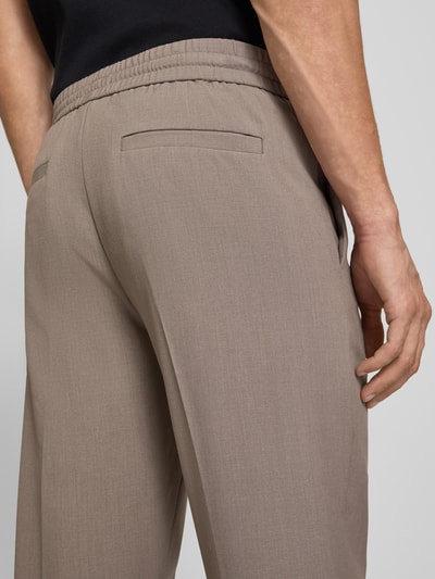 Männermodel trägt Relaxed Fit Sweatpants mit Viskose-Anteil von Lindbergh in Taupe, Elastischer-Material-Mix, Bund, Bügelfalten, Detailaufnahme Rückansicht. Bundweite 41 cm, Innenbeinlänge 79 cm, Größe M.