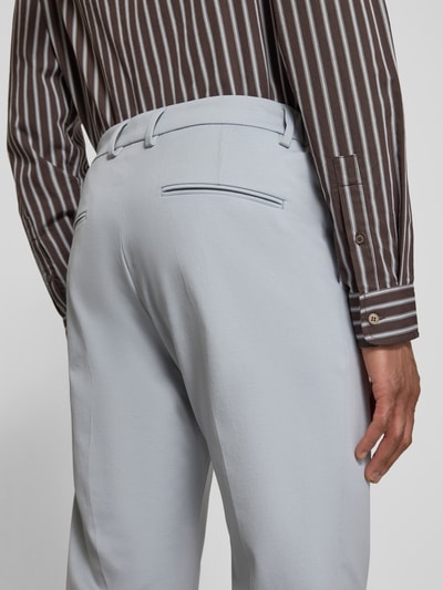 Mannenmodel draagt Straight Fit stoffen broek met persplooien model 'Ajend' van Drykorn in lichtblauw katoenmix, detailopname achterzijde. Bandwijdte maat 32/32: 44 cm, binnenbeenlengte: 75 cm, steek- en achterzakken, knoop- en ritssluiting.