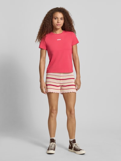 Frauenmodel trägt T-Shirt mit Print und Rundhalsausschnitt von REVIEW aus Baumwoll-Elasthan-Mix im Regular-Fit, Damen T-Shirt, leuchtendes Pink mit weißem Print, Rückenlänge bei Größe S: 51 cm, Ganzkörperansicht von vorne.