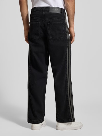 Männermodel trägt Jeans mit Eingrifftaschen von adidas Originals in Schwarz, Reine Baumwolle, Regular-Fit, Ganzkörperansicht Rückansicht.