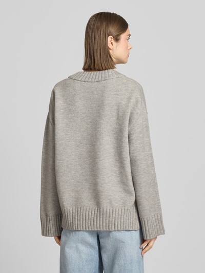 Vrouwenmodel draagt Relaxed Fit Pullover in tricotlook met V-hals van Gina Tricot in lichtgrijs, ruglengte maat S: 63 cm, mouwlengte 53 cm, relaxed fit, rugaanzicht.
