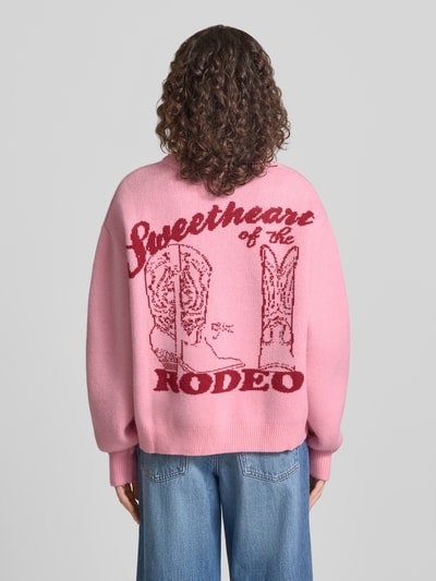 Frauenmodel trägt Relaxed Fit Pullover in Strick-Optik von ANOTHER COTTON LAB, rosa mit Logo-Stitching, Rundhalsausschnitt, Rückenlänge 58 cm, Ärmellänge 62 cm, elastische Abschlüsse, Ganzkörperansicht Rückansicht.