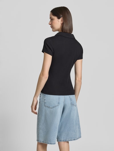 Frauenmodel trägt Damen T-Shirt mit Polokragen Modell 'Kleoh Polo' von Someday, schwarze Ripp-Optik, Baumwoll-Elasthan-Mix, Slim-Fit, Rückenlänge 60 cm bei Größe 36, Ganzkörperansicht Rückansicht.