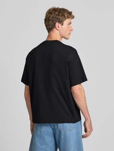 Männermodel trägt T-Shirt mit Motiv-Print Modell 'SANREMO' von JACK & JONES in Schwarz, Regular Fit, aus Baumwolle, Ganzkörperansicht Rückansicht.