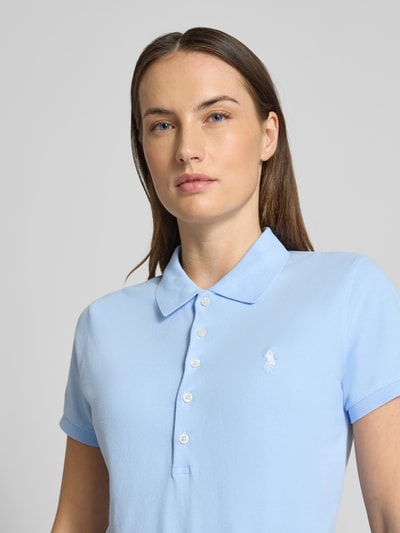 Kobiece model prezentuje Slim Fit Poloshirt aus Baumwoll-Mix od Polo Ralph Lauren, gładki jasnoniebieski pikowany bawełniany krój slim fit z krótkim rękawem i logo, zbliżenie na górną część ciała.