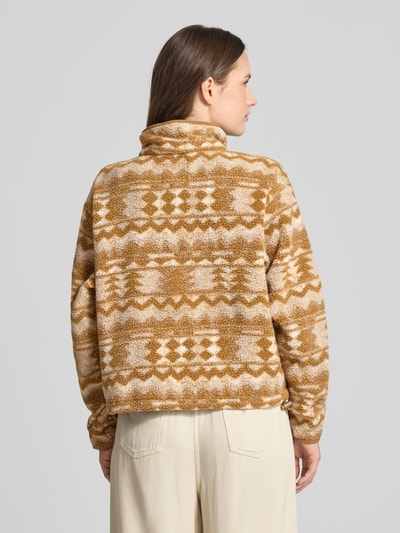 Modelka prezentuje Regular Fit Pullover mit Logo-Patch Modell 'Helvetia' od COLUMBIA w beżowo-brązowym wzorze, tekstura fleece, długość tyłu 55 cm, szerokość w rozmiarze S 58 cm, krój regular fit, widok całej sylwetki z tyłu.