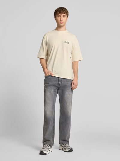 Männermodel trägt T-Shirt mit Rundhalsausschnitt und Label-Print von REVIEW in Beige, Relaxed-Fit, Reine Baumwolle, Herren T-Shirt, Ganzkörperansicht von vorne. Rückenlänge bei Größe M: 71 cm.