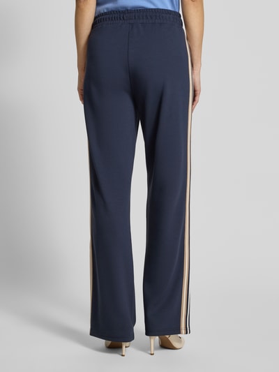 Frauenmodel trägt Sweatpants aus Viskose-Mix mit weitem Bein von Betty Barclay, dunkelblau, seitliche Streifen, elastischer Bund, Ganzkörperansicht Rückansicht.