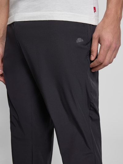 Männermodel trägt schwarze Trackpants mit elastischem Bund Modell 'EVARO' von Ellesse, Material-Mix mit Stretch, Nahaufnahme Oberschenkel.