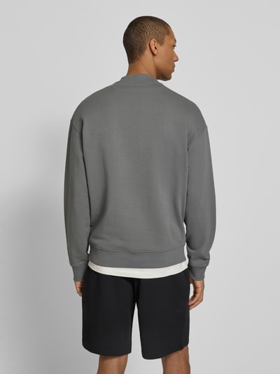 Männermodel trägt Regular Fit Sweatshirt aus reiner Baumwolle Modell 'DAPOCREW' von HUGO, grau, unifarben, Rundhals, Ganzkörperansicht Rückansicht.