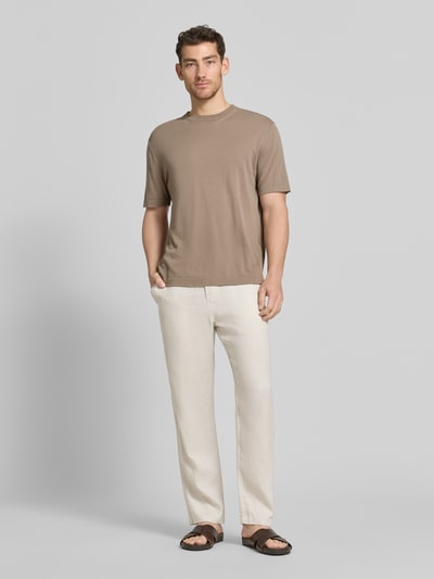 Männermodel trägt Leinenhose mit Eingrifftaschen Modell 'JABARI' von Samsøe Samsøe in Naturfarbe, Relaxed-Fit, Ganzkörperansicht von vorne.