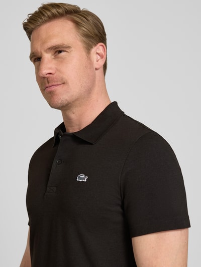 Männermodel trägt Regular Fit Poloshirt aus Baumwoll-Mix von Lacoste, Optik: Unifarben, Logo-Patch, Polokragen, Kurzarm, Nahaufnahme Oberkörper.