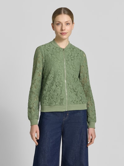 Frauenmodel trägt Regular Fit Blouson aus Baumwoll-Mix Modell 'HONEY' von Vero Moda, grün mit Florales-Allover-Muster und Häkel-Details, gerippte Bündchen, College-Kragen, Reißverschluss, Optik:Allover-Muster, Materialverarbeitung: Häckel, Nahaufnahme Oberkörper.