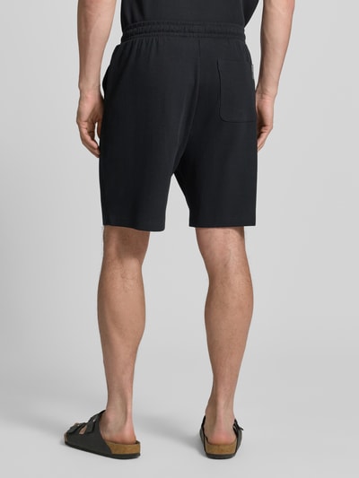 Mężczyzna nosi Relaxed Fit Sweatshorts aus reiner Baumwolle od Tom Tailor Denim, kolor jednolity, krój relaxed fit, średni stan, wykończenie w pasie elastyczne, boczne kieszenie, tylna kieszeń, bawełna, dzianina o wyraźnej fakturze, widok całej sylwetki z tyłu.