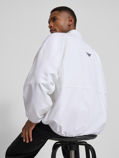 Männermodel trägt Bomberjacke mit Stehkragen und Logo-Print von EA7 Emporio Armani in Weiß, elastische Abschlüsse, Rückenansicht.