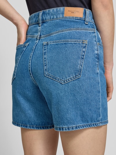 Frauenmodel trägt Bermuda Leg Jeansshorts aus reiner Baumwolle von Marc O'Polo Denim, mittleres Blau, Twillstruktur, 5-Pocket-Design, Ganzkörperansicht Rückansicht.