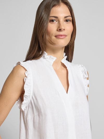 Modelka kobieta nosi Regular Fit Blusentop mit Leinen-Anteil Modell 'VIVA' von Selected Femme, efekt: jednolity kolor, krój regular fit, stójka z falbanami, dekolt w serek, zapięcie: ukryta listwa guzikowa, bez rękawów, falbany na ramionach, detal tekstury lnu, zbliżenie na górną część ciała.