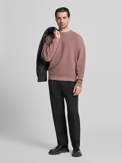 Männermodel trägt Regular Fit Sweatshirt aus reiner Baumwolle Modell 'DAFFLYN' von HUGO in Rosa, strukturierter Jacquard, Ganzkörperansicht von vorne.