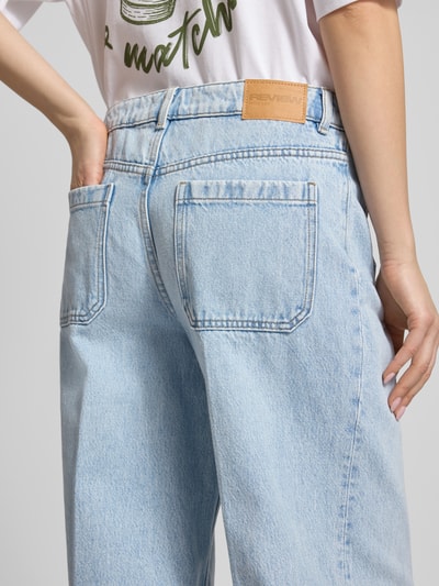 Frauenmodel trägt Wide Leg Jeans mit aufgesetzten Taschen von Review aus reiner Baumwolle, hellblaue Jeansoptik, Detailaufnahme Rückansicht.