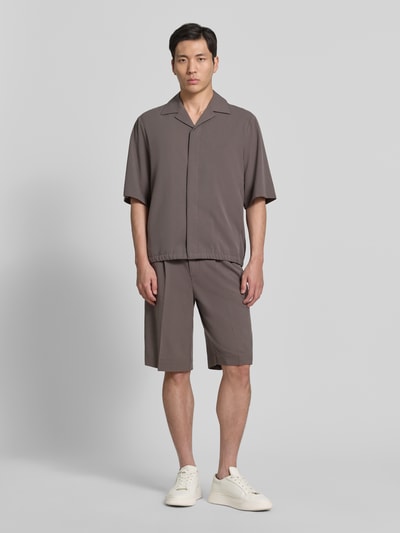 Männermodel trägt Straight Fit Shorts mit Viskose-Anteil von Lindbergh in Braun, mit Bundfalten, Gesäßtaschen und Haken-Reißverschluss, Ganzkörperansicht von vorne.