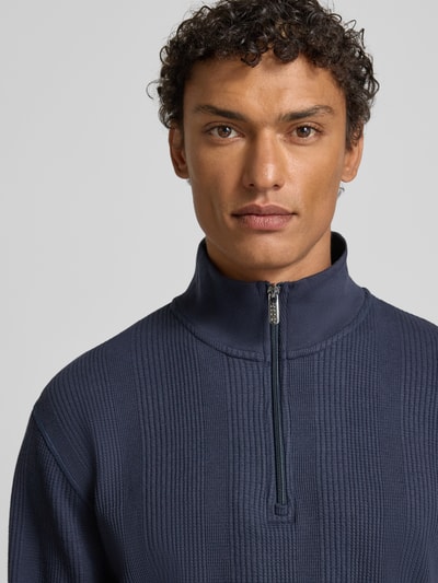 Männermodel trägt Regular Fit Troyer aus Baumwoll-Mix Modell 'STRUCTURE' von BOSS in Dunkelblau, Struktur-Muster, Nahaufnahme Oberkörper.