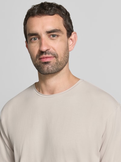 Männermodel trägt T-Shirt mit Rundhalsausschnitt und Rollsaum von Scotch & Soda aus reiner Baumwolle im Relaxed Fit, Nahaufnahme Oberkörper.