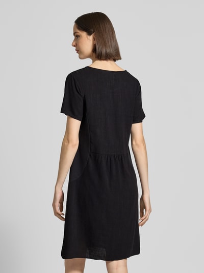 Frauenmodel trägt Relaxed Fit Kleid aus Viskose-Mix Modell 'Tara' von ZABAIONE in Schwarz, Kurzärmelig, Struktur fein, Rückenlänge 96 cm, Leinen-Viskose-Anteil, Ganzkörperansicht Rückansicht.