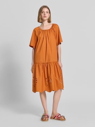 Frauenmodel trägt Knielanges Kleid mit Lochstickerei und Rundhalsausschnitt von Christian Berg Woman in Orange, Reine Baumwolle, Straight Fit, Knielänge, mit Raffungen, Allover-Lochstickerei am Rockteil, Ganzkörperansicht von vorne.