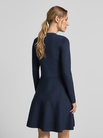 Kobiece modelka nosi sukienkę mini z mieszanki wiskozy Model 'Abito Maglia' od Liu Jo White, granatowa, ozdobne obszycie, długość tyłu 85 cm, szerokość w rozmiarze S 40 cm, długość rękawów 35 cm, lekko rozkloszowany fason, długi rękaw, widok całej sylwetki z tyłu.