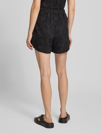Kobiece modelka nosi Regular Fit Stoffshorts aus reiner Baumwolle Modell 'PCGINGER' od PIECES, czarne, jednolite, widok całej sylwetki od tyłu.