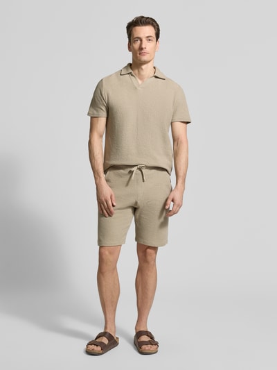 Mężczyzna model nosi Regular Fit Poloshirt aus Baumwoll-Mix von MCNEAL, mieszanka bawełny i elastanu, pika, krótki rękaw, wykładany kołnierz, dekolt w serek, długość tyłu w rozmiarze M: 69 cm, jasnobeżowy, gładka powierzchnia, pełny widok z przodu
