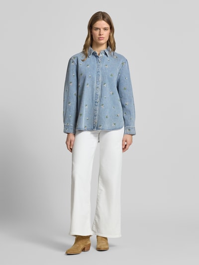 Modelka nosi bluzkę jeansową Relaxed Fit Jeansbluse aus reiner Baumwolle Modell 'VERA' od Only, denim, hafty kwiatowe, zapięcie ukryte, długi rękaw, bawełna, widok całej sylwetki z przodu.
