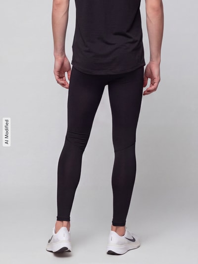 Männermodel trägt schwarze Slim Fit Sport-Leggings mit Logo-Print von Under Armour, glatte Textur, Ganzkörperansicht Rückansicht, KI-modifiziertes Bild.