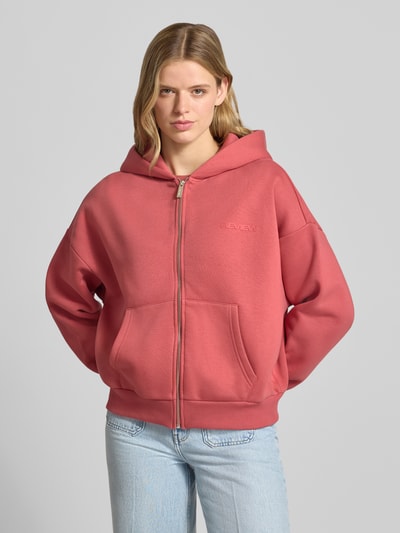 Frauenmodel trägt Relaxed Fit Sweatjacke mit Kapuze und Logo-Print von REVIEW aus Baumwoll-Mix mit Reißverschluss, Känguru-Tasche, Ganzkörperansicht von vorne.