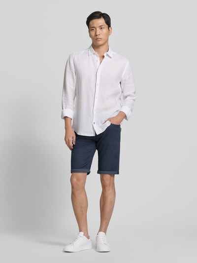 Männermodel trägt Jeansshorts mit Label-Detail von Pierre Cardin in Dunkelblau, Baumwoll-Mix mit Stretch-Anteil, Eingrifftaschen, Umschlag, Regular-Fit, Ganzkörperansicht von vorne.