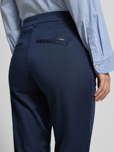 Frauenmodel trägt Hose in verkürzter Passform Modell 'MARON' von Brax aus Baumwoll-Lyocell-Mix mit Eingrifftaschen, Nahaufnahme Rückansicht.