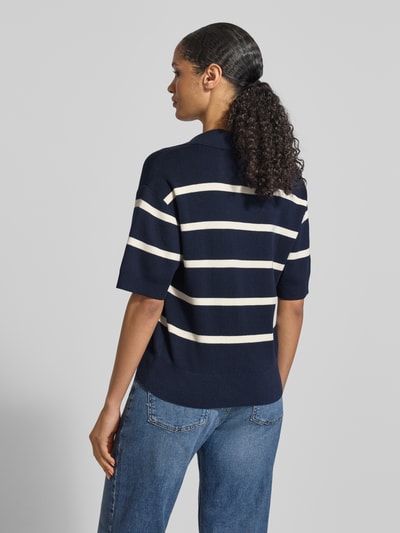 Frauenmodel trägt Regular Fit Pullover aus reiner Baumwolle von Tommy Hilfiger, marineblau mit weißen Streifen und Polokragen aus Feinstrick, Ganzkörperansicht Rückansicht.